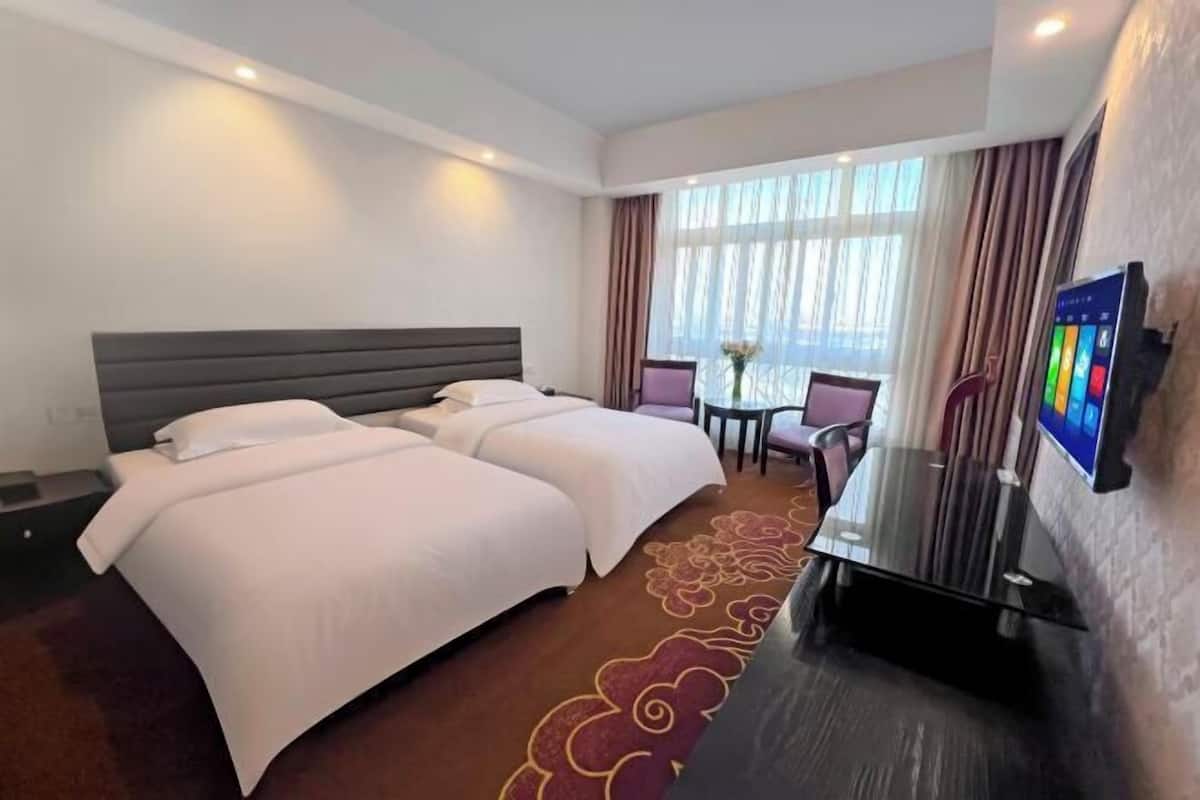 Una habitación de hotel con una cama grande, un escritorio y un televisor.