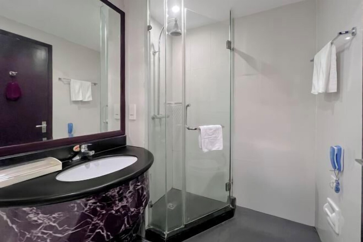 Een moderne badkamer met een douchecabine van glas, een marmeren wastafel en een grote spiegel.