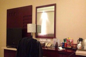 A hotel room with a desk, a flat-screen TV, a telephone, a coffee maker, and a mirror. - Huadu International Hotel (Xiangtan)