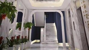 A modern interior with a marble staircase, white columns, and potted plants.