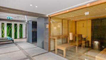 Un moderno vestíbulo de hotel con un separador de vidrio, bancos de madera y una recepción con diseño de pared verde.
