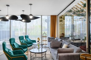 A modern living room with green armchairs, a grey sofa, and a glass coffee table. - Mercure Tokaj Center (Tokaj)