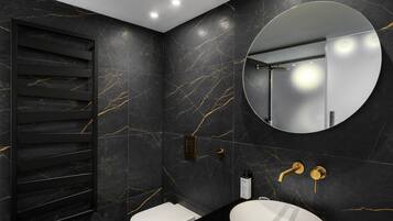Un baño moderno con pared de mármol negro, un espejo redondo, un lavabo blanco y un inodoro.