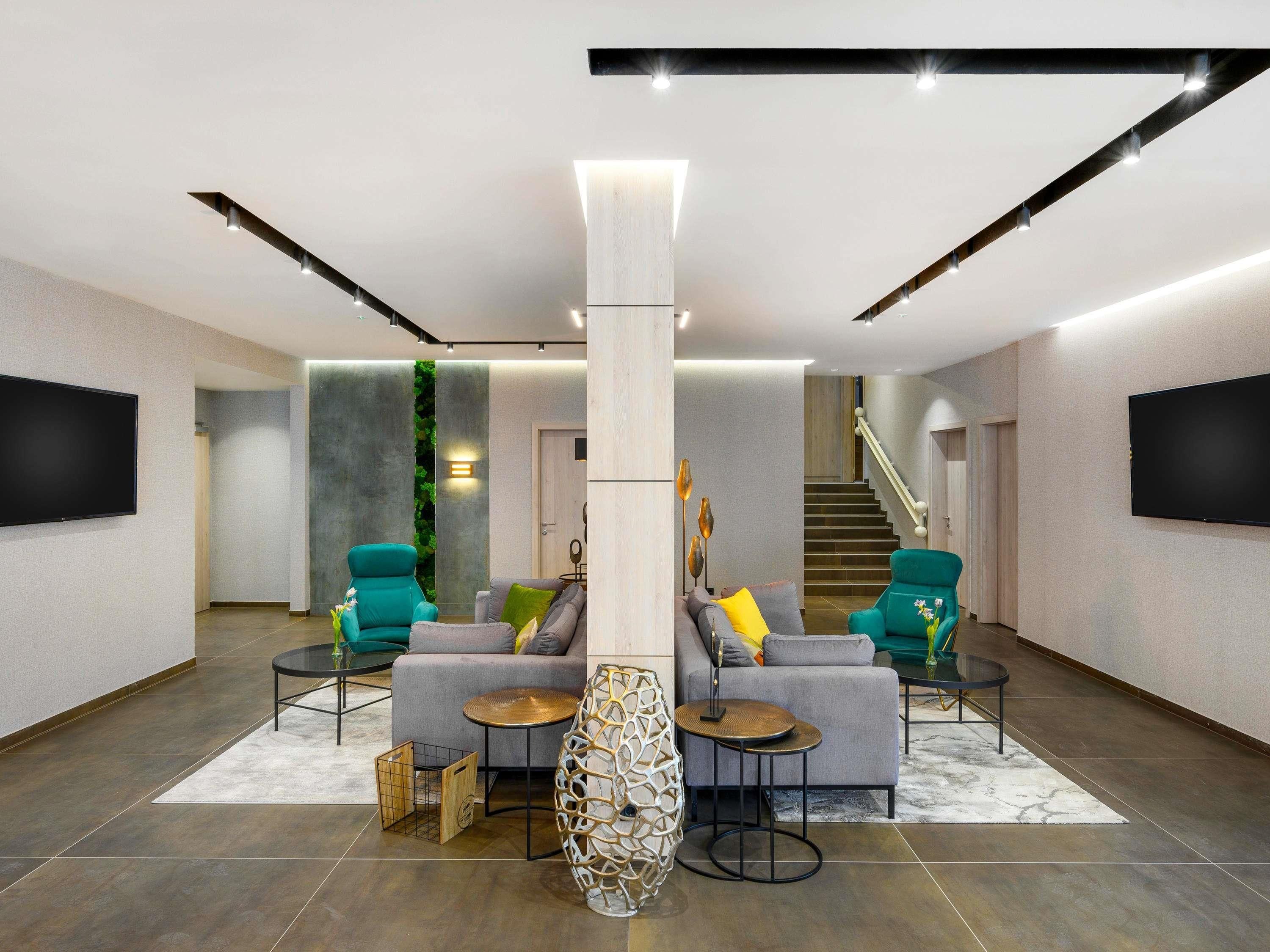A modern living room with a sectional sofa, two armchairs, a coffee table, and a TV mounted on the wall.