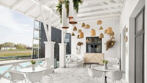 A modern outdoor patio with white furniture, a pool, and decorative hanging lights. - Mercure Tokaj Center (Tokaj)