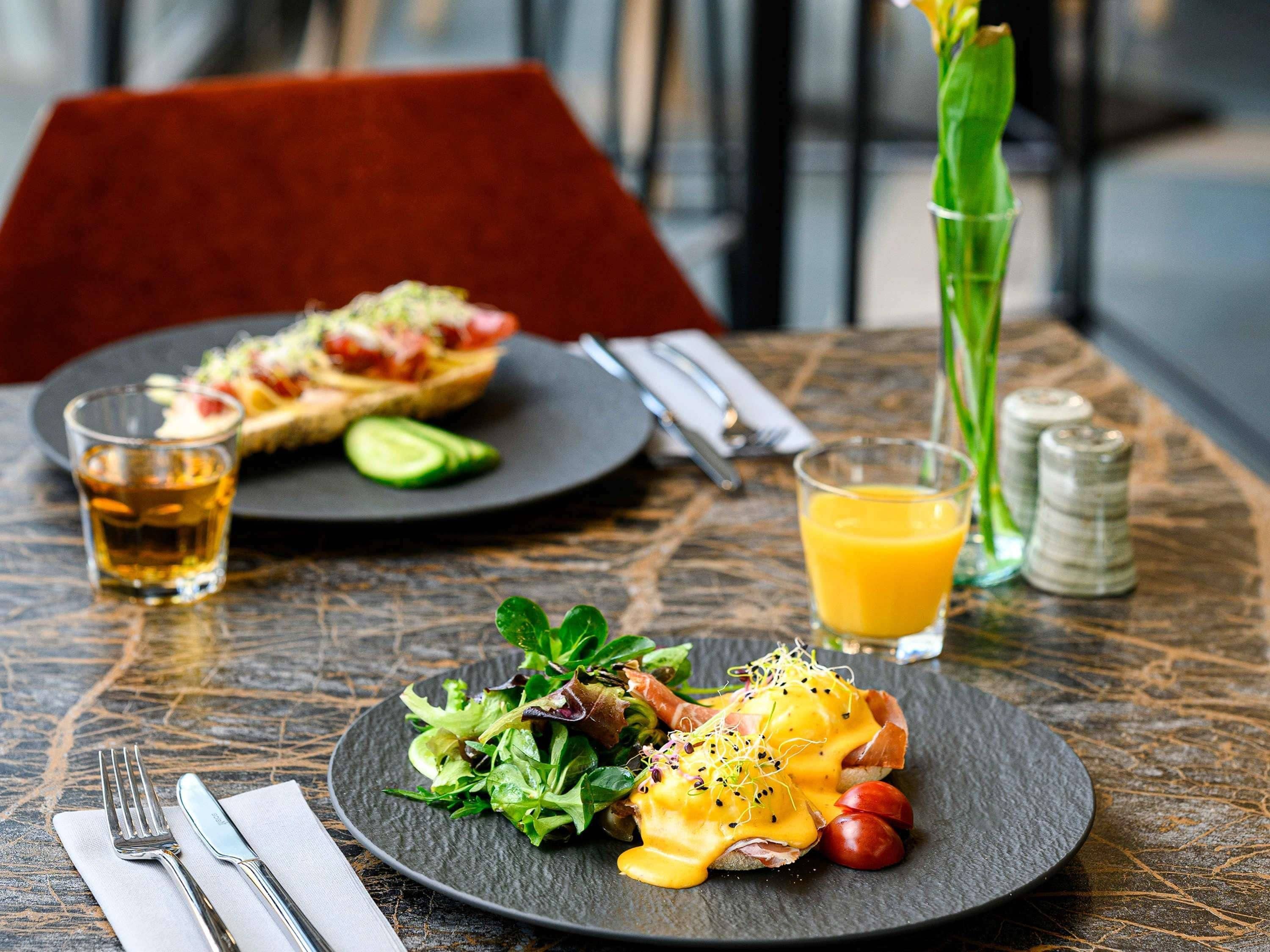 A table with a meal consisting of eggs benedict, a salad, and a glass of orange juice.