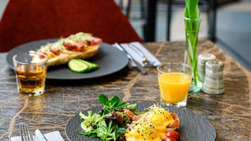 A table with a meal consisting of eggs benedict, a salad, and a glass of orange juice.