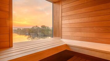 Un interior de madera con un amplio ventanal que da a un cuerpo de agua y árboles.