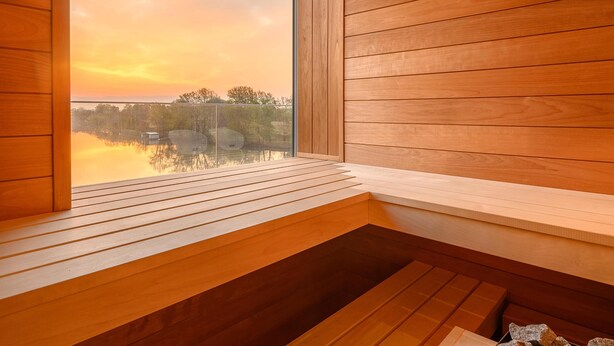A wooden interior with a large window overlooking a body of water and trees. - Mercure Tokaj Center (Tokaj)