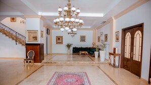 A spacious lobby with a large chandelier, a grand staircase, and a plush green sofa. - Richmond Hotel (Constanta)