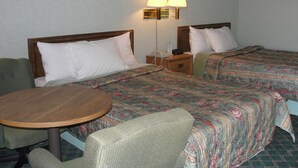 Habitació d'hotel amb dos llits, una taula rodona i dues cadires. Hi ha làmpades penjades a la paret i quadres amb marc sobre els llits.