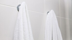 Un bany amb parets revestides de rajoles blanques i un penjallotges de tovalloles.
