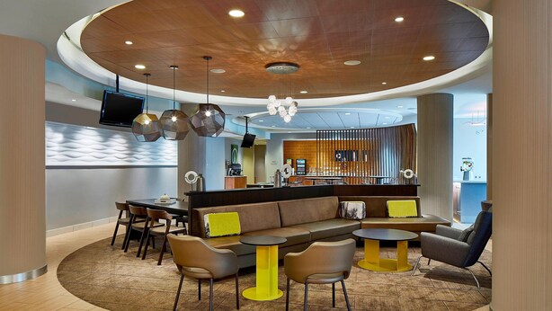 A modern lobby with a curved ceiling, seating area, and a bar.