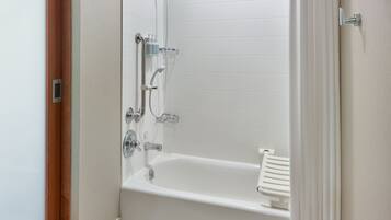 Un baño con una bañera blanca, zona de ducha y un perchero para toallas.