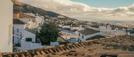 A coastal town with white buildings and terracotta roofs, overlooking the sea.