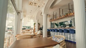 A spacious dining area with a wooden table and wicker chairs, a bar with stools, and a chandelier. - La Fonda Hotel (Benalmádena)