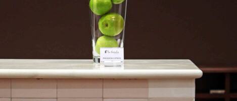 A tiled counter with a glass vase containing green apples.