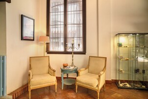 A room with two chairs, a lamp, a window, and a glass display case.
