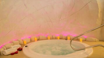 Een jacuzzi met een metalen trap, omringd door kaarsen en handdoeken met de naam 'Katharina'.