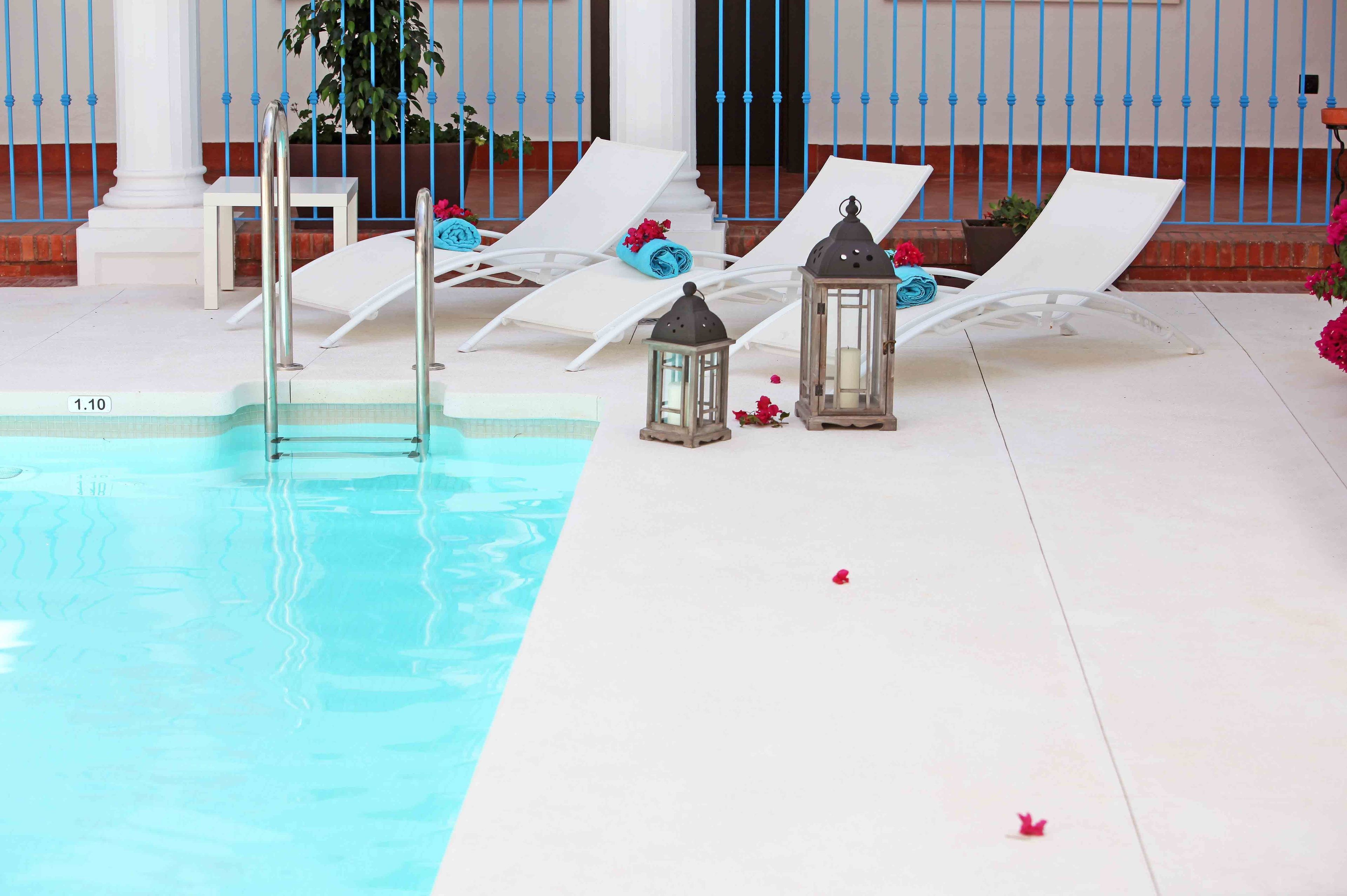 A pool area with lounge chairs, a ladder, and lanterns.