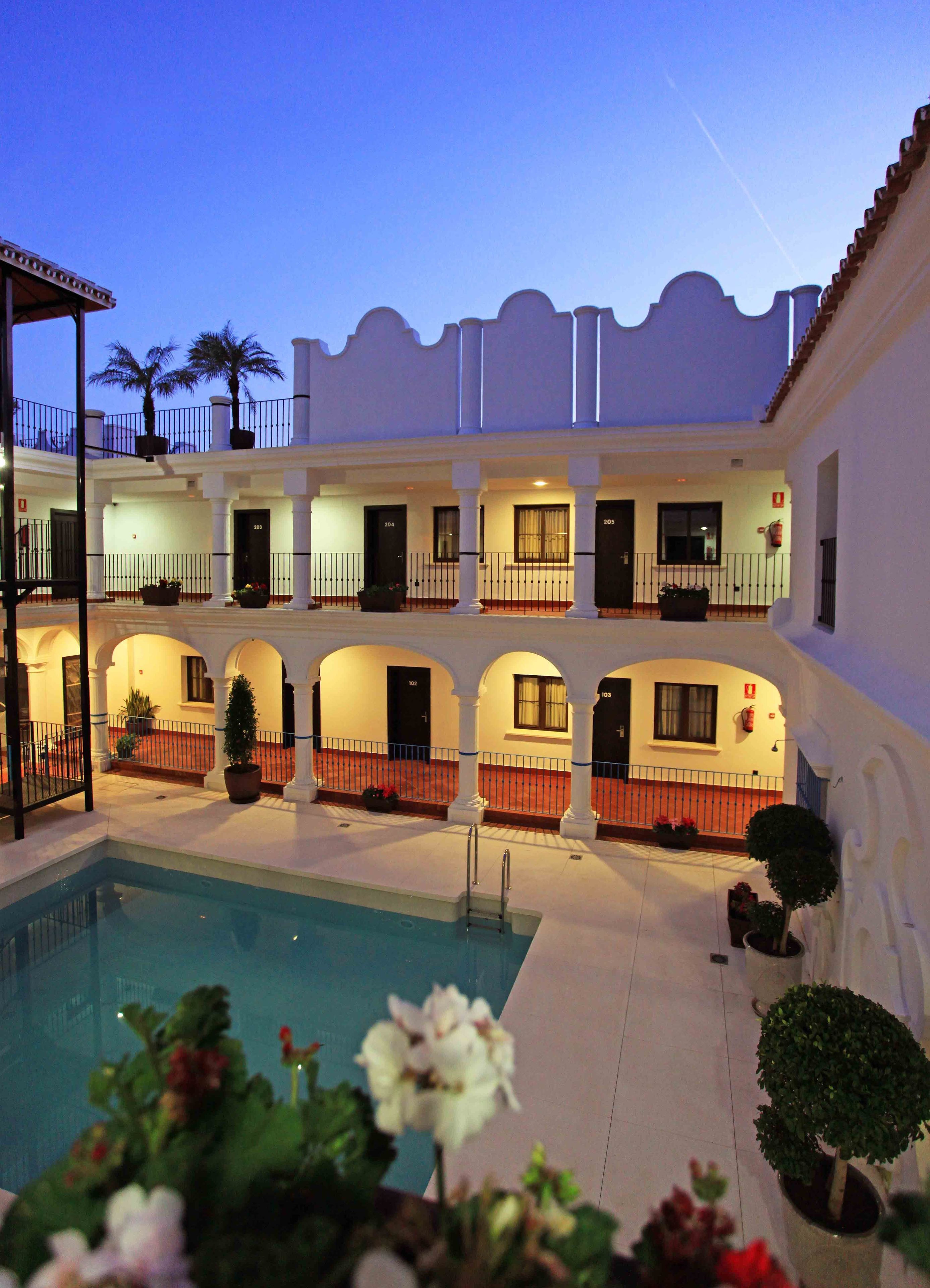 A hotel with a pool, multiple balconies, and a courtyard.