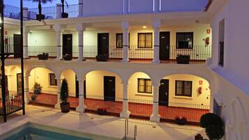 A hotel with a pool, multiple balconies, and a courtyard.