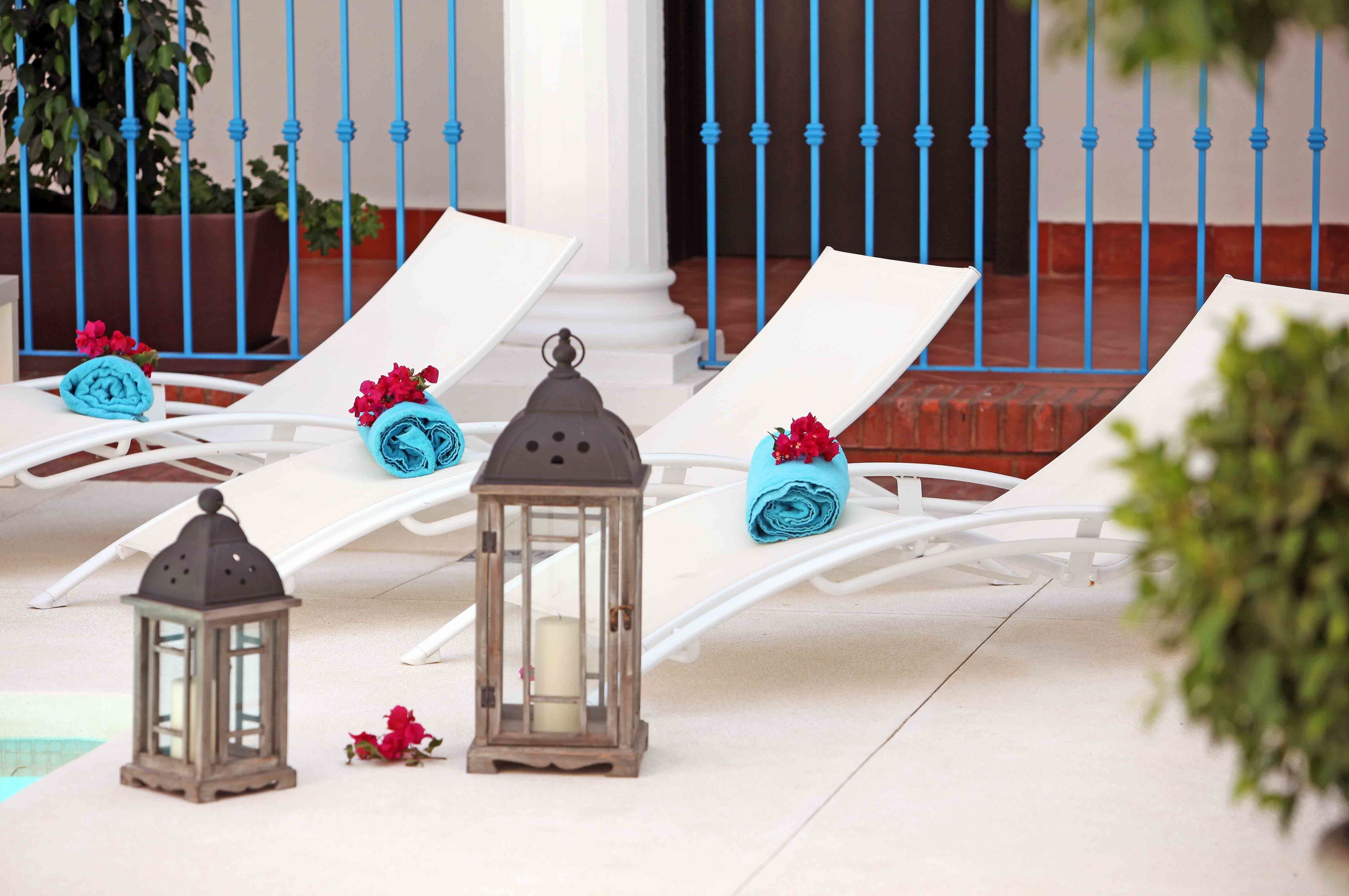 Zona de piscina amb gandules blanques, tovalloles blaves i fanals.