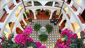 A multi-level atrium with a checkered floor, potted plants, and seating areas. - La Fonda Hotel (Benalmádena)