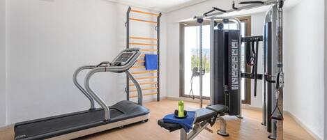 Ein Fitnessstudio mit Laufband, Kraftgeräten und einer Klimmzugstange.