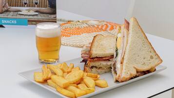 Un sándwich, una cerveza en un vaso y una porción de papas fritas sobre una mesa.