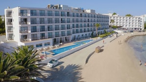 Un hotel moderno con varios balcones, piscina y zona de playa.