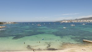 Zona costera con aguas cristalinas, embarcaciones y una playa de arena.