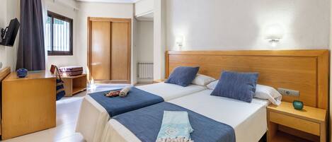 A hotel room with two beds, a wooden nightstand, a desk, and a TV.