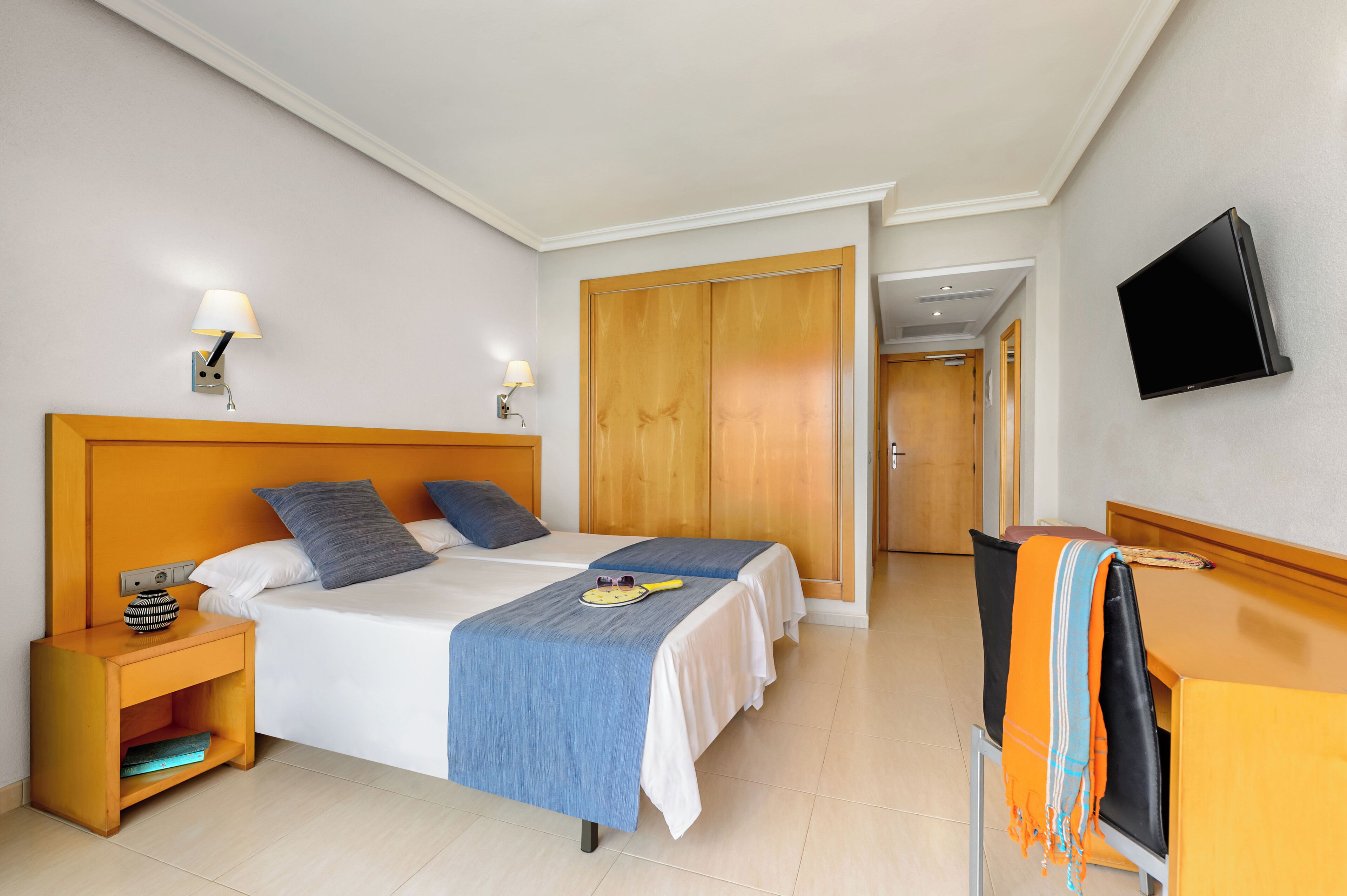 Una habitación de hotel con cama, mesitas de noche, televisión y armario.