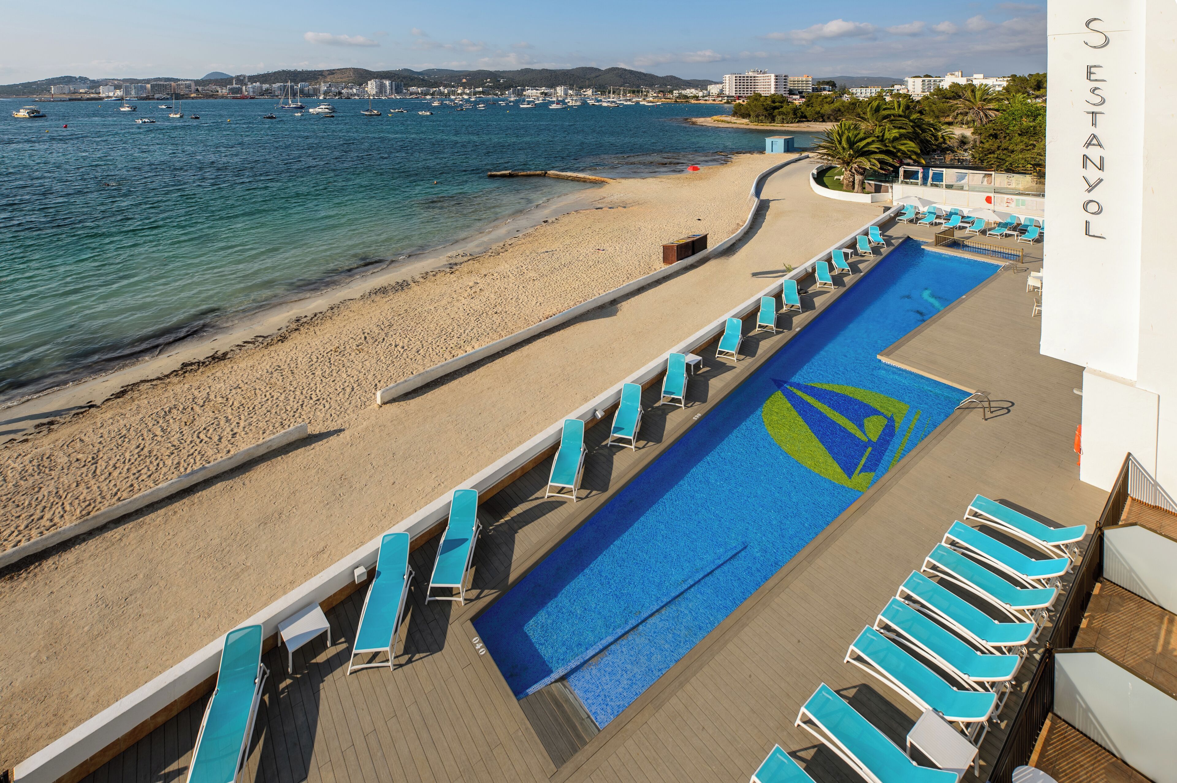 Un espace piscine avec des chaises longues et une vue sur la plage et la mer.