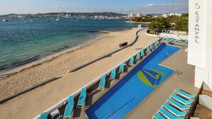 A pool area with lounge chairs and a view of the beach and sea. - Hotel Vibra S´Estanyol (Sant Josep de sa Talaia)