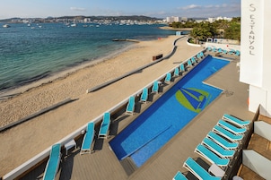 Zona de piscina con sillas de descanso y vistas a la playa y al mar.