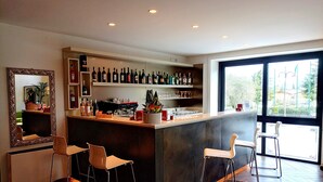 Zona de bar moderna amb un taulell central, dos tamborets i un mirall gran.