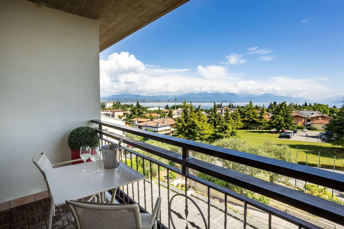 A balcony with a table, chairs, and a potted plant.
