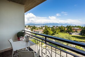 Ein Balkon mit Tisch, Stühlen und einer Topfpflanze.