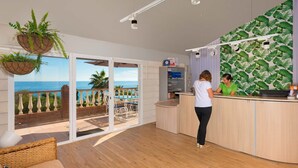 A reception area with a view of the ocean, a reception desk, and a counter with a plant. - Olée Nerja Holiday Rentals By Fuerte Group (Torrox)