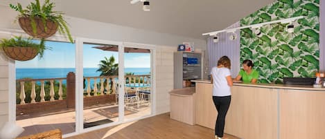 A reception area with a view of the ocean, a reception desk, and a counter with a plant.