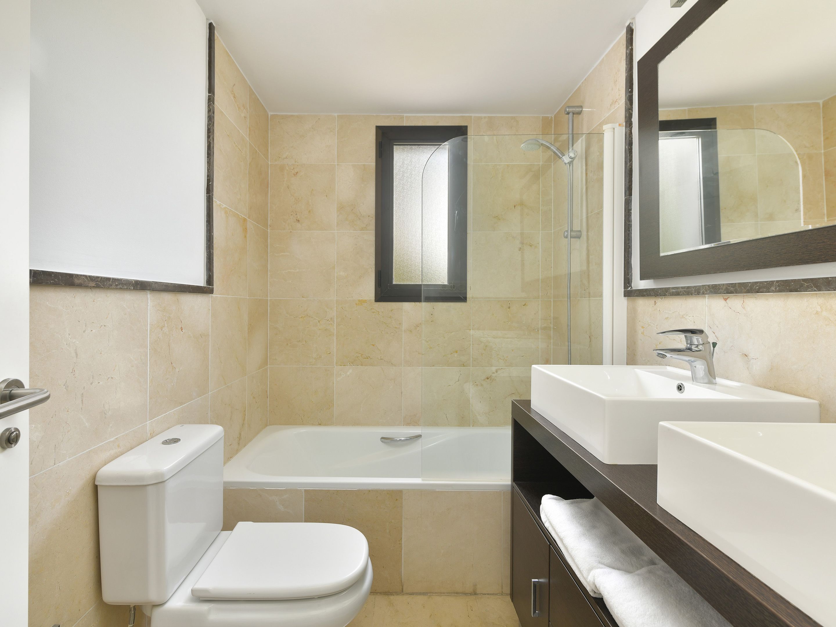 A bathroom with a toilet, a bathtub, and two sinks.