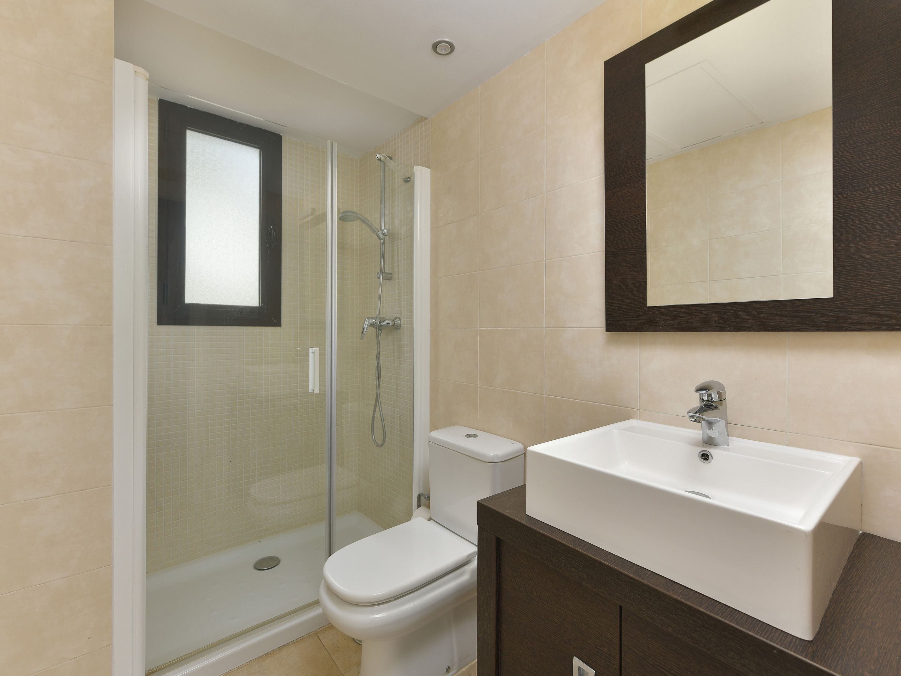 Une salle de bain avec une douche à parois de verre, des toilettes et un lavabo avec un miroir au-dessus.