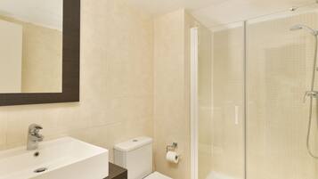 A bathroom with a sink, toilet, and glass-enclosed shower.