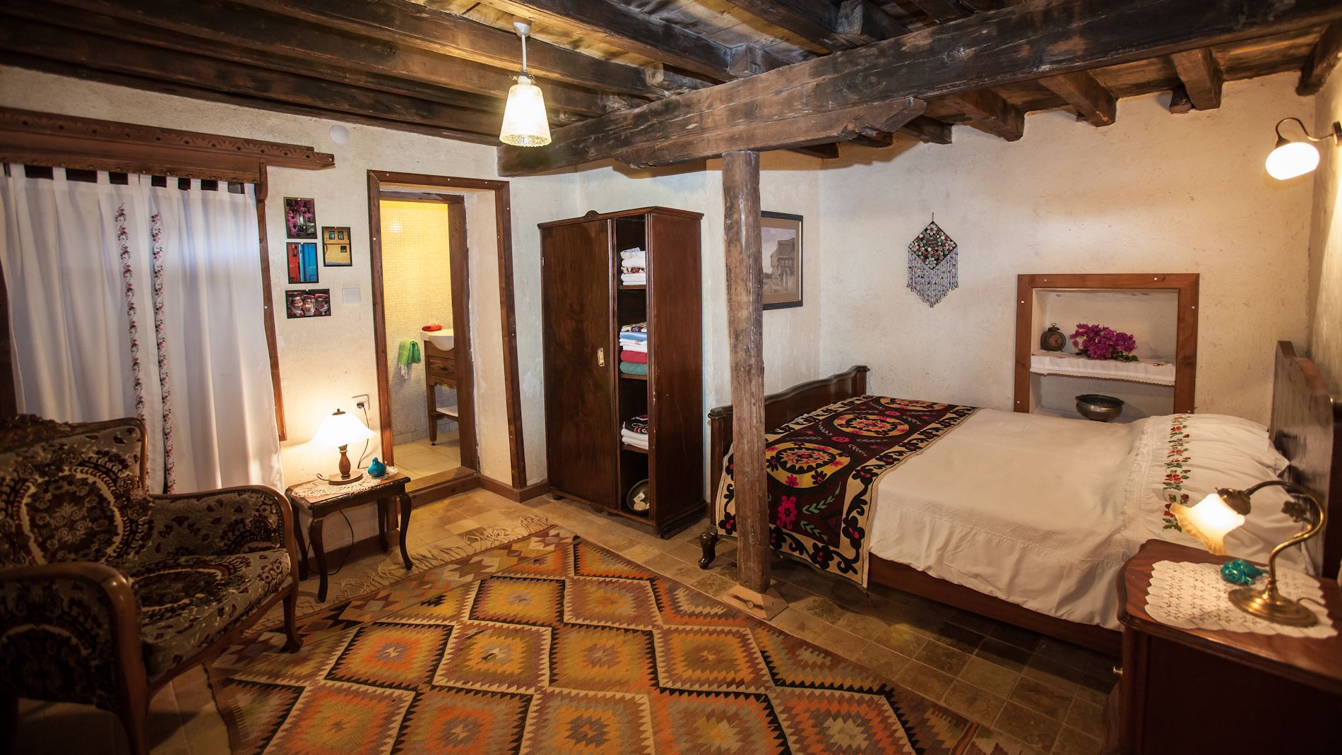 Una habitación tradicional con una cama, una silla, un armario de madera y un tapiz estampado.
