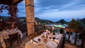 Un espace de restauration en plein air, avec des tables dressées pour un repas, offrant une vue sur une piscine et un paysage pittoresque.