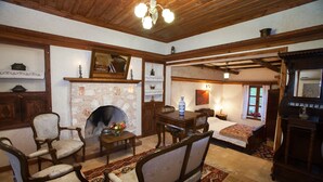 Une chambre à l’ancienne, dotée d’une cheminée en pierre, de meubles en bois et d’un lit recouvert d’une couvre-lit à motifs.