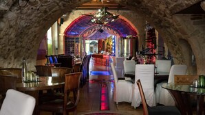 An underground restaurant with stone walls, wooden furniture, and a red-lit floor. - Avli Lounge Apartments (Rethymno)