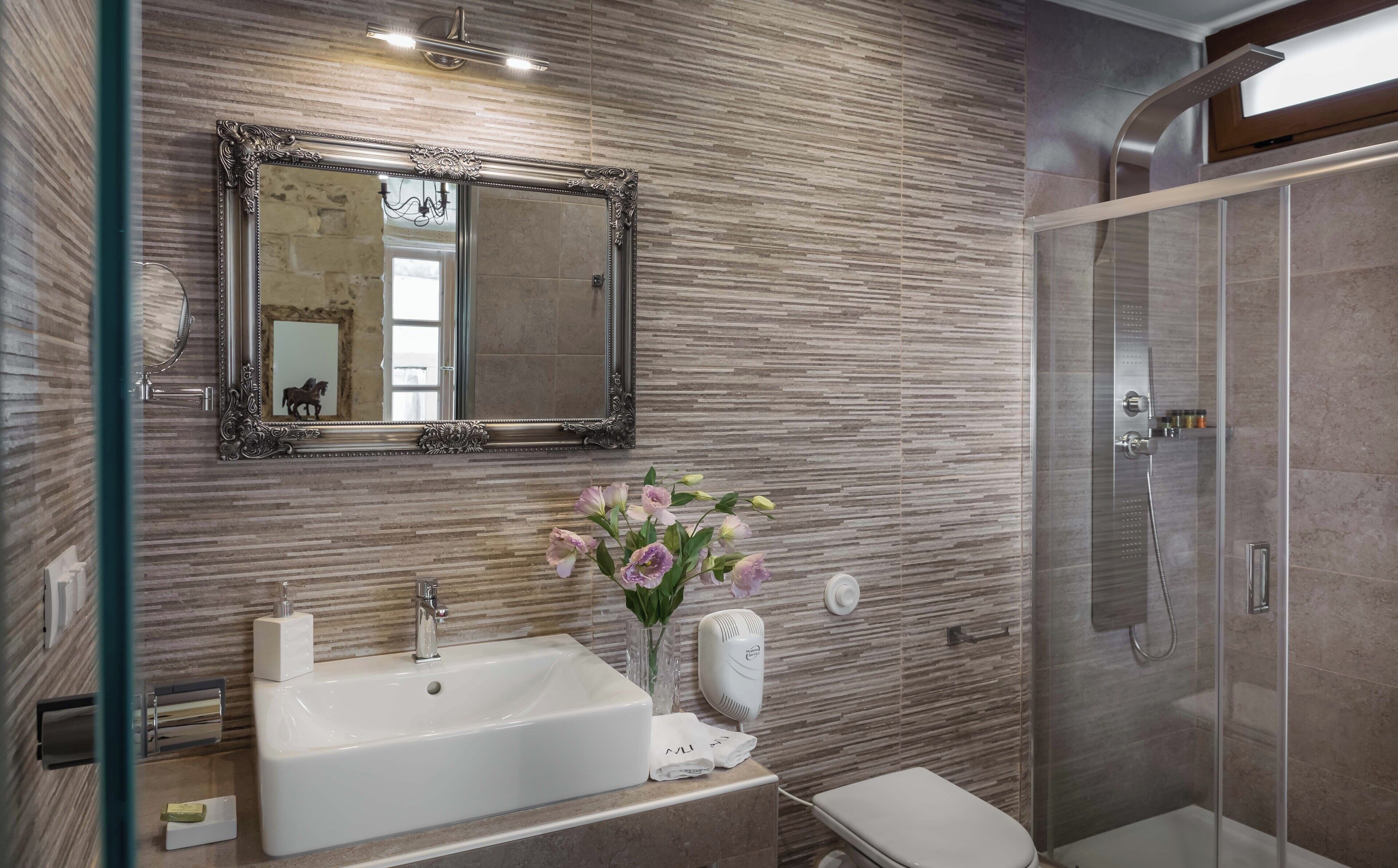 Ein modernes Badezimmer mit großem Spiegel, Waschbecken, Toilette und Dusche.